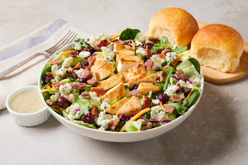 Bob Evans Cranberry Pecan Chicken Salad in a white bowl, on a table next to two dinner rolls.